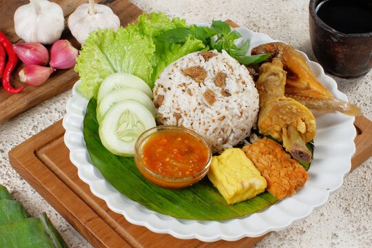 Nasi Tutug Oncom. Traditional Sundanese meal of rice mixed with fermented soybean; accompanied with grilled prawn, tempeh, tofu, salted fish, vegetables and chili paste