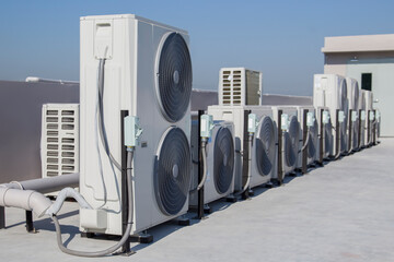 Air conditioning (HVAC) on the roof of an industrial building with blue sky and clouds.	