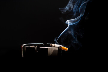 Closeup of cigarette on ashtray with a beautiful wisp of smoke