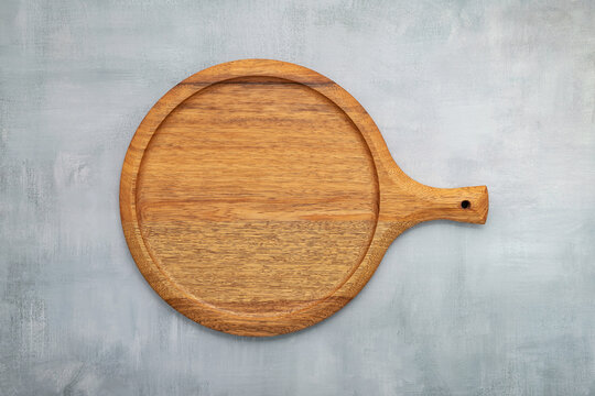 Empty wooden pizza platter set up on grey concrete. Pizza tray on grey concrete background flat lay and copy space.