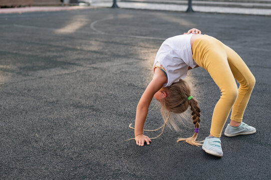 Caucasian girl doing bridge exercise on sports ground outdoors. 