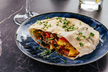 turkish pita with meat, vegetables and sauce on a plate