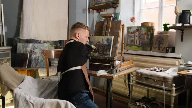 a man with disabilities is engaged in painting in a workshop