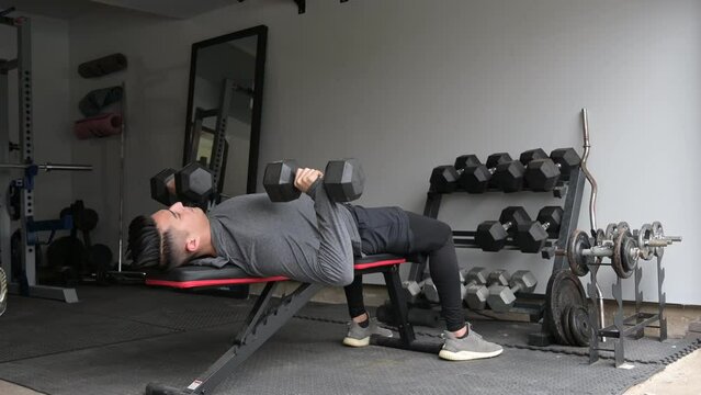 Video of Young Man Bench Pressing Dumbbells at In Home Garage Gym