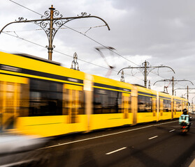 stock photo of moving tram passing by person riding motorbike