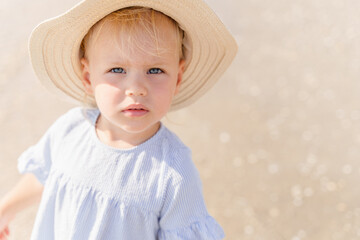 Little girl in a straw hat on the beach near the sea, close-up