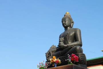 Buddha statue with a pot of flowers in his hands.