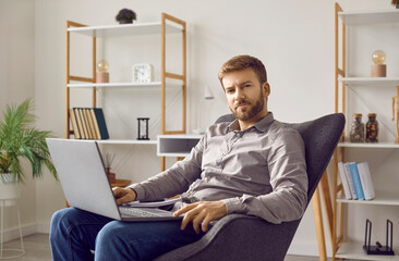 Portrait of a young successful businessman at home. Relaxed young business man with a modern laptop...