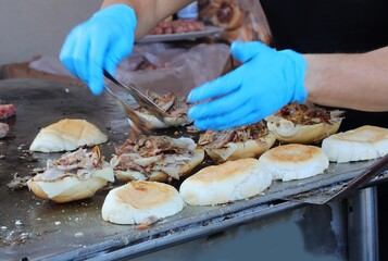 cook in the street food stall preparing a stuffed sandwich with meat and vegetables