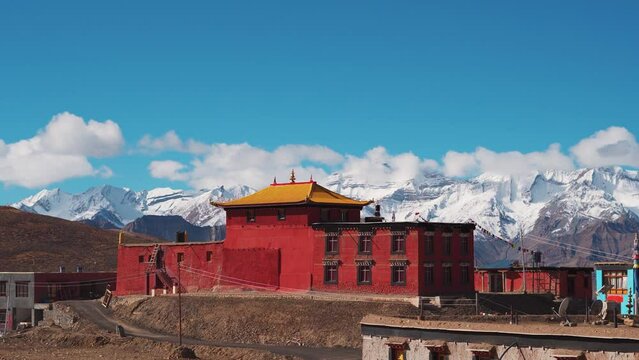 4K shot of Tangyud Monastery at Komic village in front of the snow covered Himalayan mountain peaks covered by clouds at Spiti Valley, India. World's highest monastery in front of the mountains.