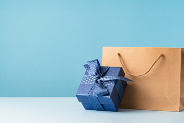 small Luxury gift box with a blue bow paper bag and agenda. Side view. Fathers day or Valentines day gift for him. Corporate gift concept or birthday party. Festive sale copy space