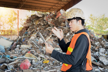Asian engineer wearing hard hat and protective vest standing on tablet explaining job details in...