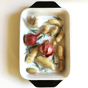 Overhead view of onions with garlics and gingers in tray on table