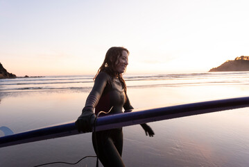 Woman carrying surfboard along the Oregon coast
