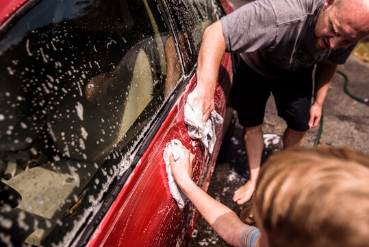 Close up of father and son washing car together