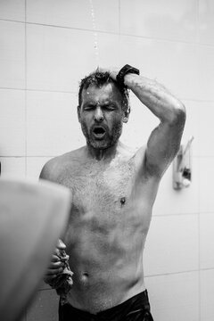 A man surfer washes in an outdoor shower after surfing.