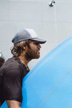 A man surfer washes in an outdoor shower after surfing.