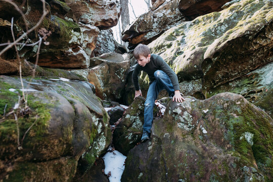 Boy scrambling over rocks on hike in forest