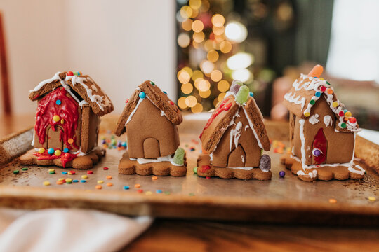Row of gingerbread houses sit on cookie sheet on kitchen table