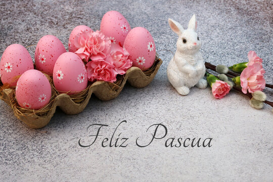 Tarjeta de Pascua: Huevos de Pascua rosas con flores y conejito de Pascua con la inscripción happy easter.
