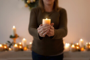 Kobieta modli się trzymając w dłoniach zapaloną świecę. Zmartwychwstanie pańskie wiara i nadzieja w modlitwie