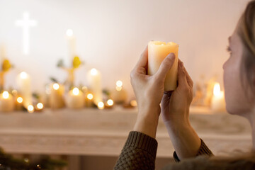 Kobieta modli się trzymając w dłoniach zapaloną świecę. Zmartwychwstanie pańskie wiara i nadzieja w modlitwie - obrazy, fototapety, plakaty