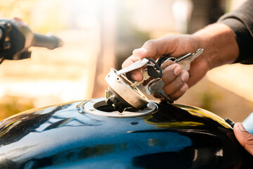 Hands opening the gas tank of the motorcycle with the key. Hand opening the gas tank of the motorcycle, Motorcyclist opening the gas tank of the motorcycle.