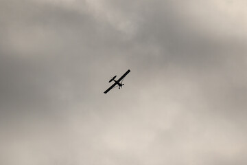 Fototapeta na wymiar Small plane flying in the sky against dark clouds