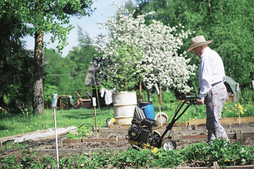 The farmer is digging a garden. The harvester plows the garden. The gray-haired grandfather mows...