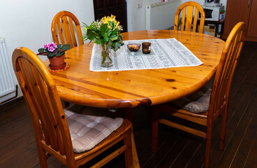 Pine wood dinning table with four chairs , focus on the flowers on residential house interior.