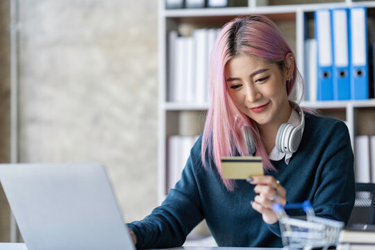Portrait of a young Asian businesswoman enjoying online shopping with credit card payments. on laptops and tablets at the office