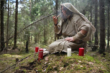 A man in a cassock spends a ritual in a dark forest