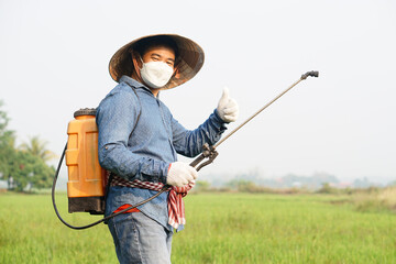 Asian farmer is spraying organic fertilizer at paddy field. Thumb up.  Concept using friendly...