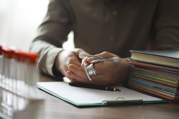 Male doctor search information in book and writtnig prescription, medical stethoscope on the desk at clinic. Medical knowledge and education concept.