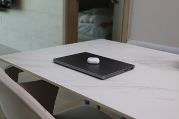 가정집 책상위에 놓여진 노트북과 블루투스 이어폰