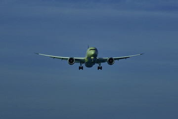 Airplane landing on blue sky background.