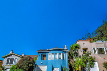 Neigborhood landscape with blue house against sky in San Francisco California. Facade of two-storey...