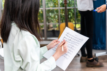 female student sitting taking notes music teacher.