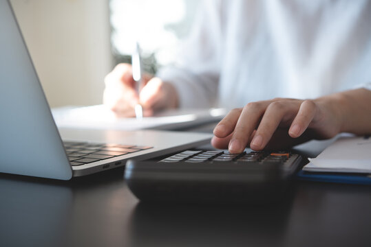 Close up of business woman accountant hand using calculator and laptop computer for calculating finance on desk office. business financial accounting concept