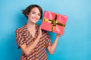 Portrait of lovely cheerful person beaming smile arms hold giftbox empty space isolated on blue color background