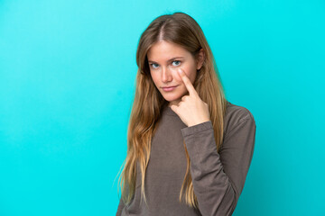 Young blonde woman isolated on blue background showing something