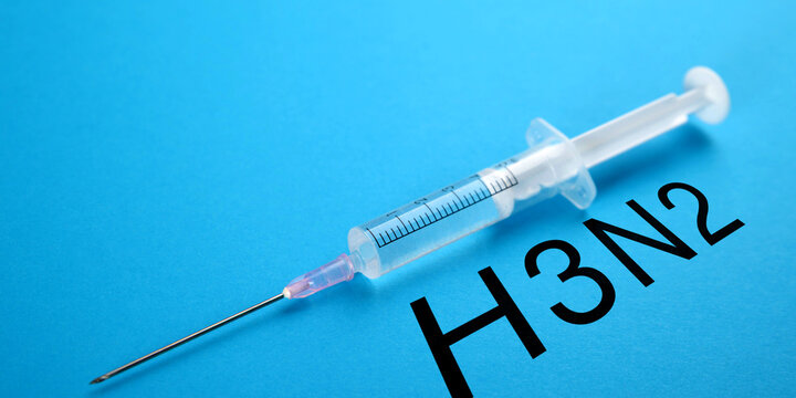Closeup of a syringe on blue background with text H2N3. Health and medicine concept.