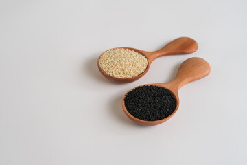Black and white sesame seed in wooden spoons