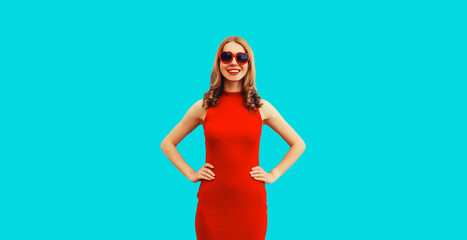 Summer portrait of beautiful young woman posing wearing dress and red heart shaped sunglasses on blue background
