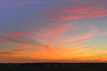 A stunning sunset with orange, yellow and red colors on a blue sky and clouds 