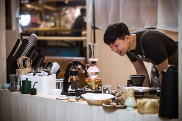 Professional coffee maker - Barista using coffee siphon brewing hot espresso at coffee shop coffee brewing syphon alternative method. Startup Business Concept.