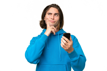 Young handsome man isolated on green chroma background using mobile phone and thinking