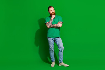 Full length photo of cool suspicious man wear t-shirt arm chin looking empty space isolated green...