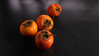 Persimmon fruits on dark background, place for text