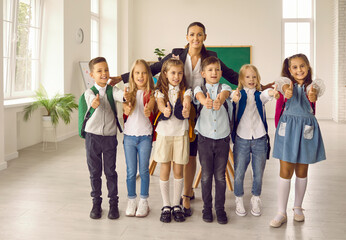 Happy female enthusiastic teacher hugs students of her elementary class. Group photo for parents....